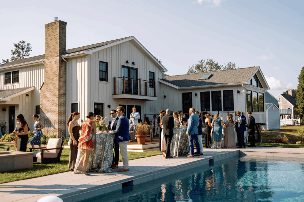 Guests talking at standing tables near a pool during cocktail hour.