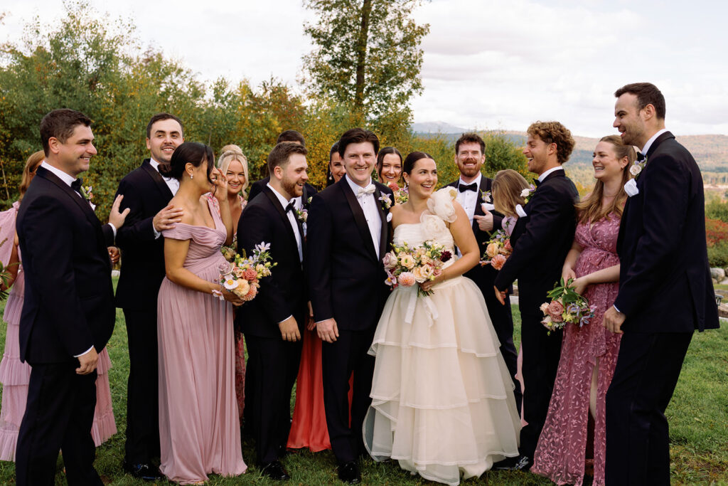 A bride and groom laugh with the bridal party and groomsmen.