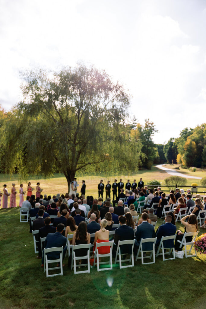An outdoor wedding with guests watching the bride and groom get married.
