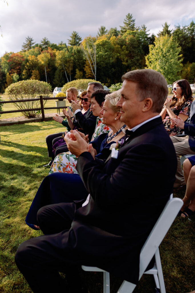 Outdoor wedding with guests sitting and clapping. 