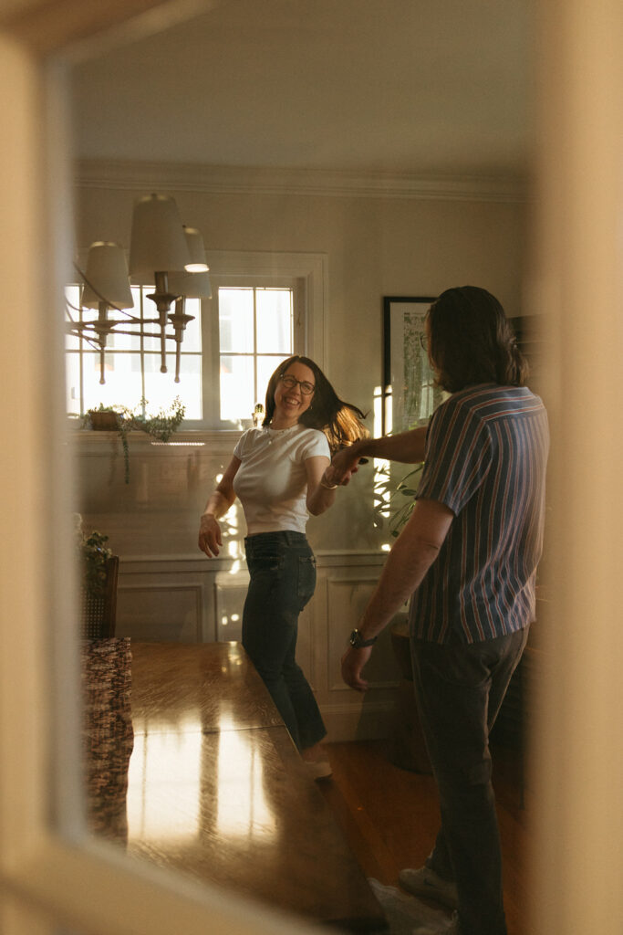 A creative engagement photo of a man and woman dancing in the living room together.