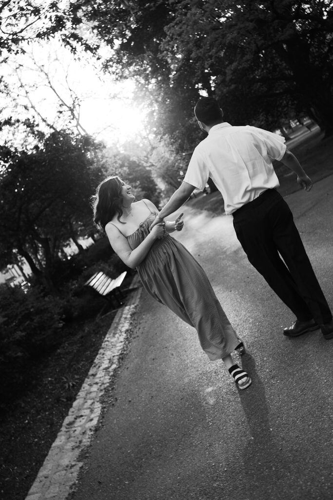 A man and a woman dancing in the street together in candid engagement photos.