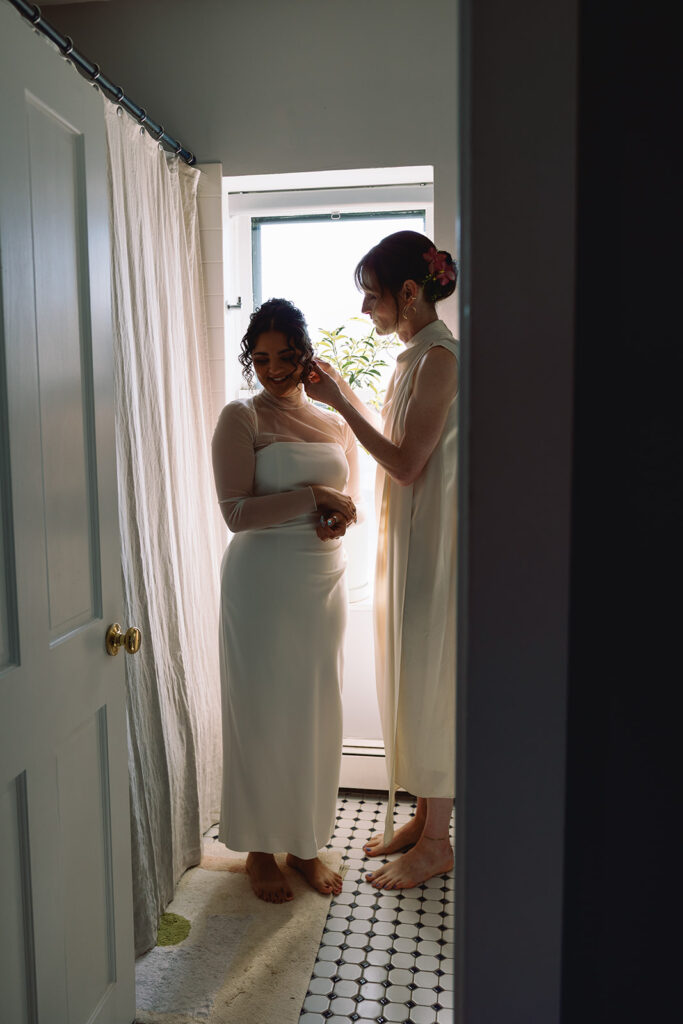 brides help each other get ready at Boston apartment for their fall restaurant wedding 