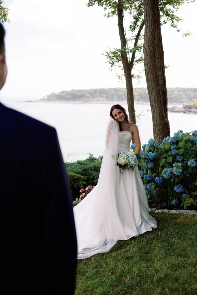 bride looks over at groom on York Maine harbor before their wedding 