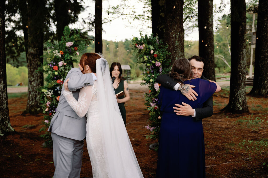 bride and groom hug parents at beginning of wedding ceremony in New Hampshire woods