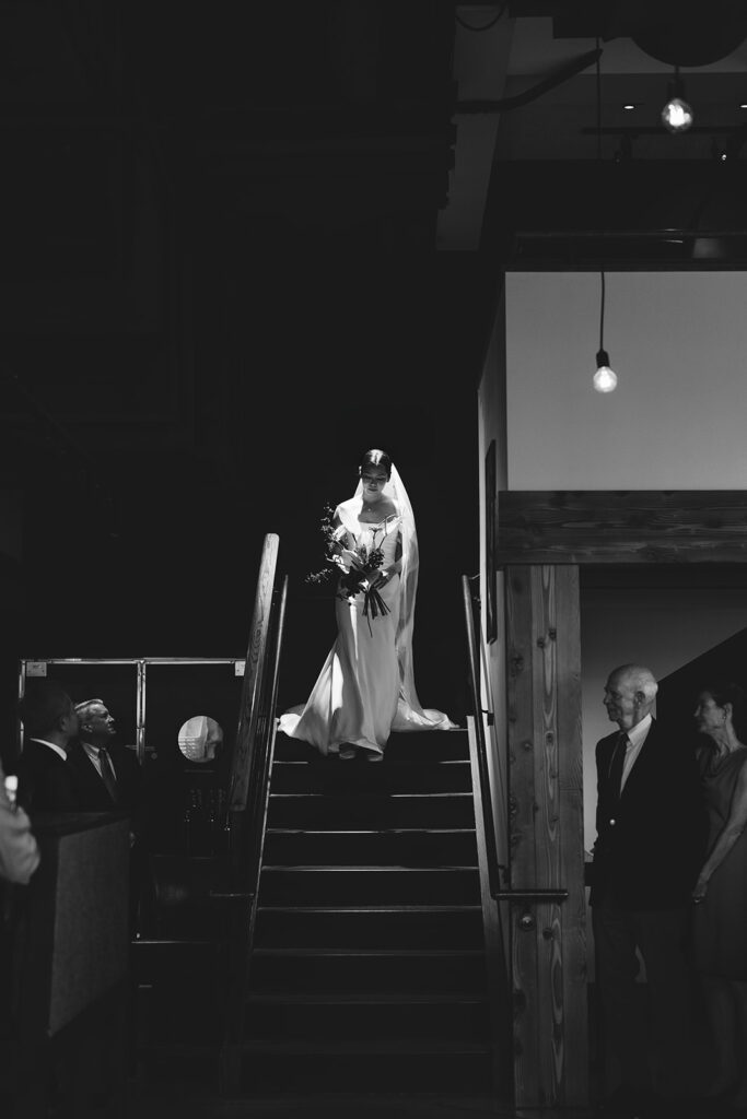 moody artistic photo of bride walking down stairs and entering ceremony at PAGU wedding in Cambridge MA