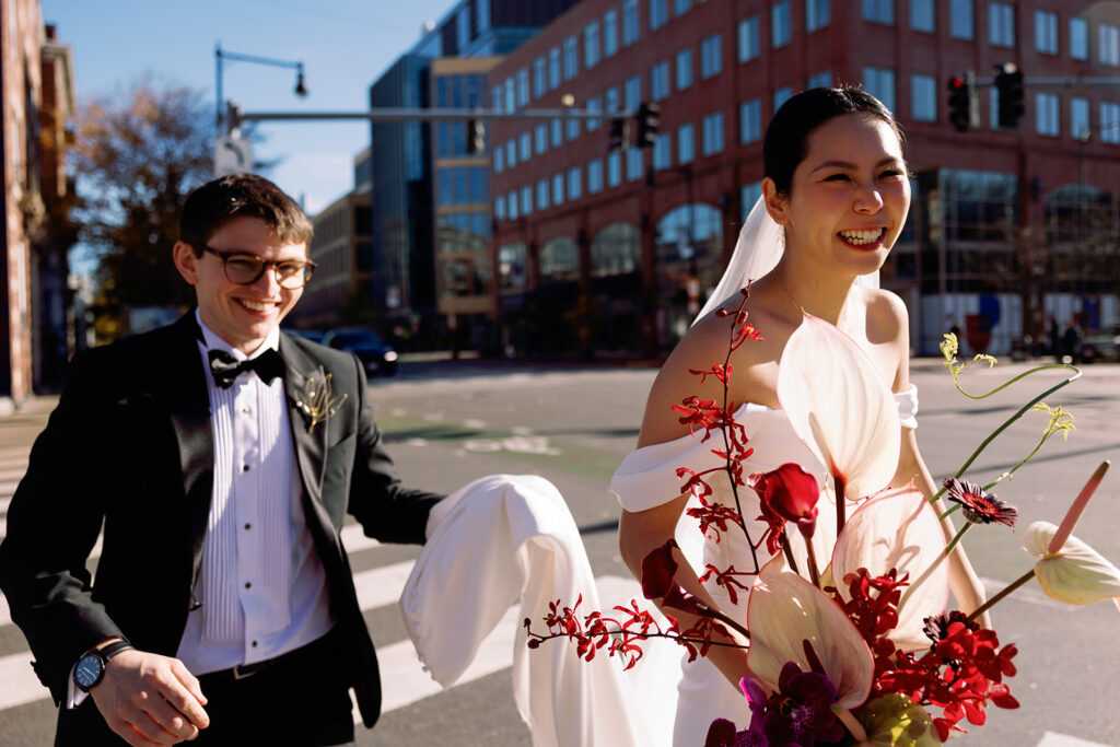 vibrant colorful candid portrait of bride and groom in the city streets of Central Square while the sun hits her artistic bouquet designed by Rococo Floral 